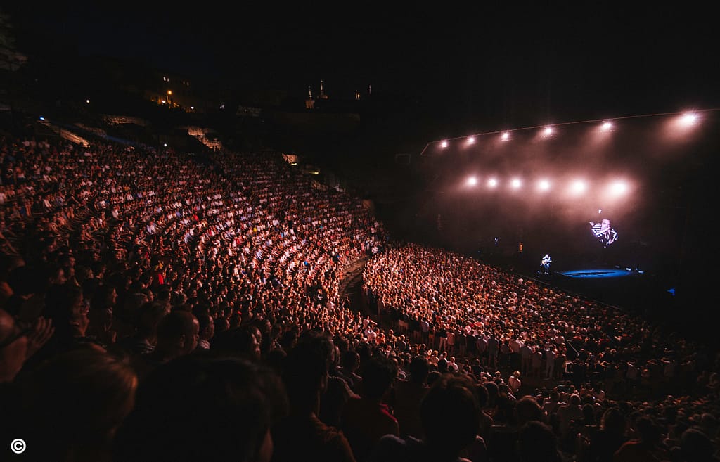 Artiste captivant la foule lors d'un concert de chanson française aux Nuits de Fourvière.